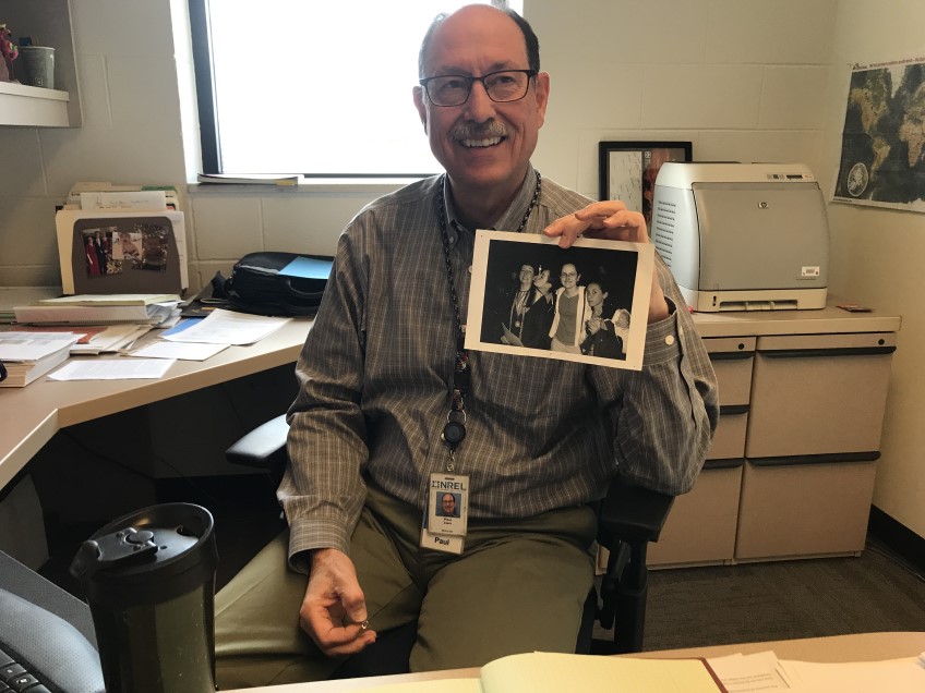 A man holds up a photo in an office setting.