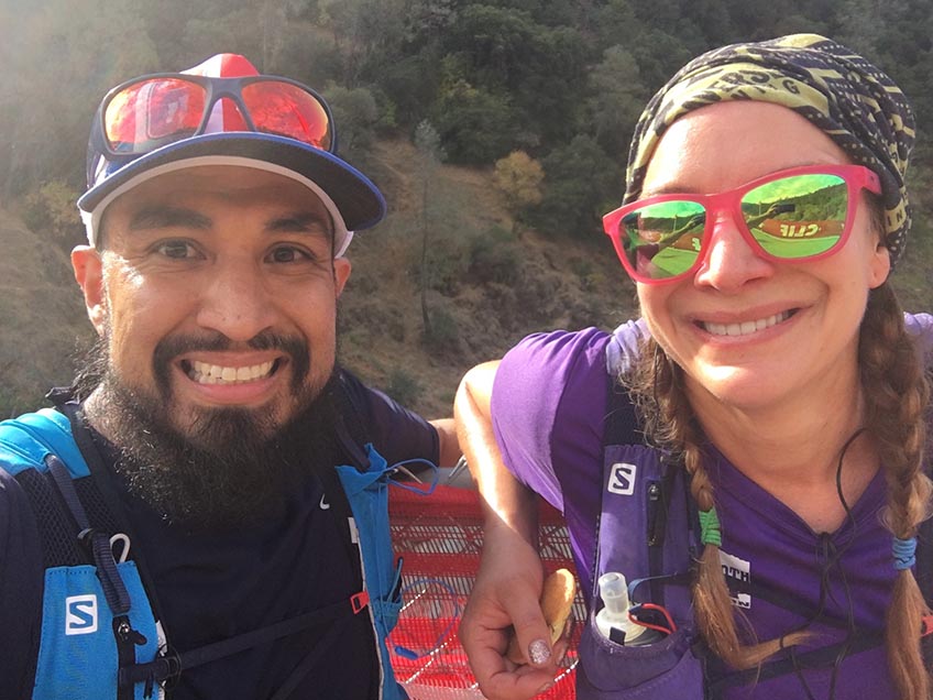 A man and a woman smile in running outfits.