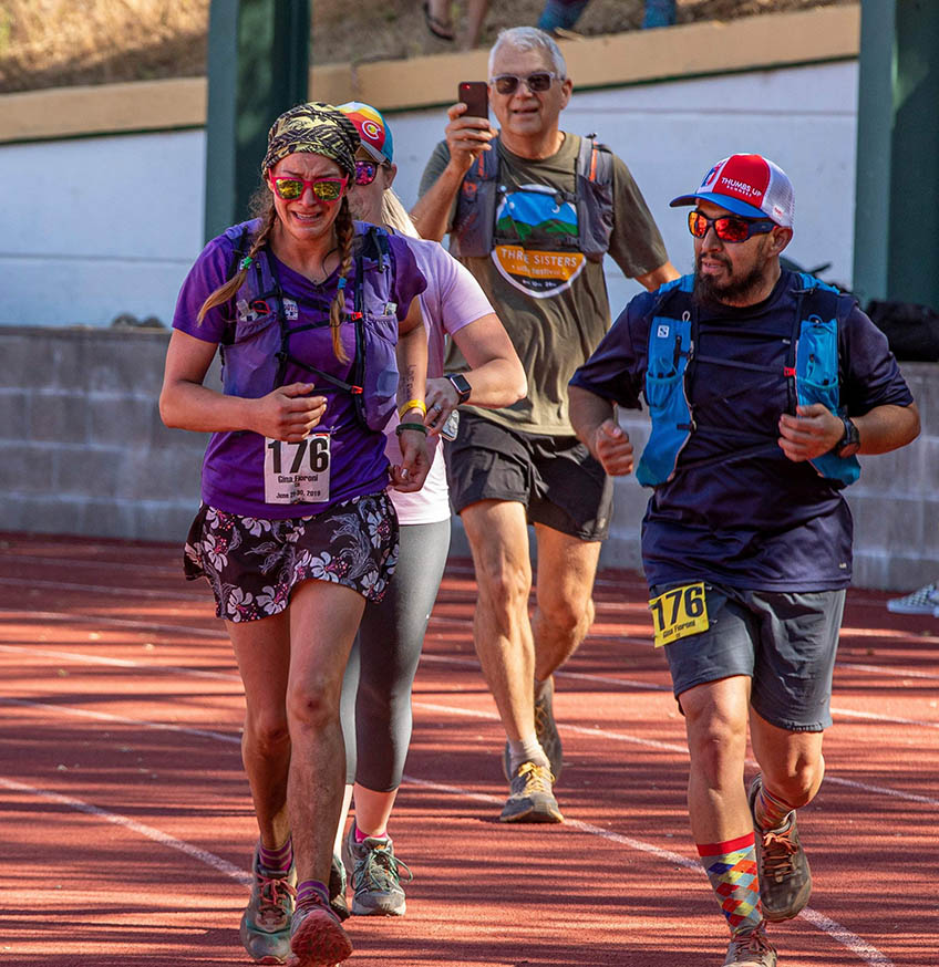 A woman and three others running on a track.