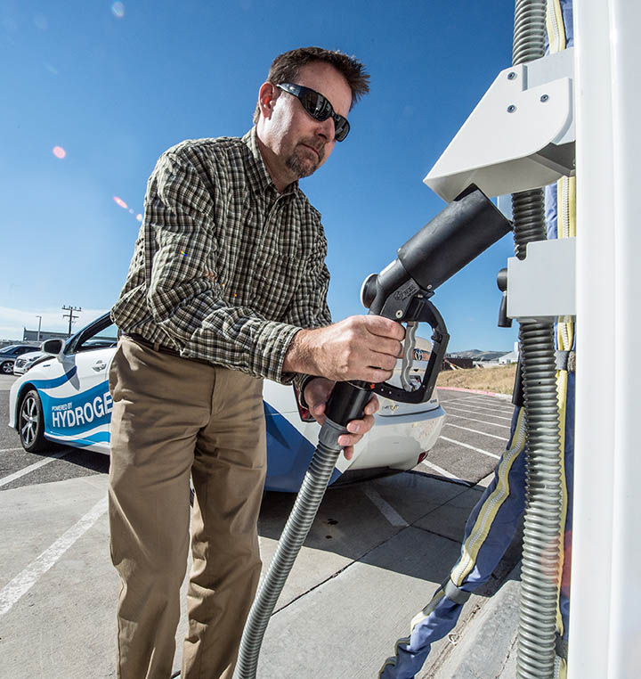 A man grips the handle of a hydrogen fueling nozzle.