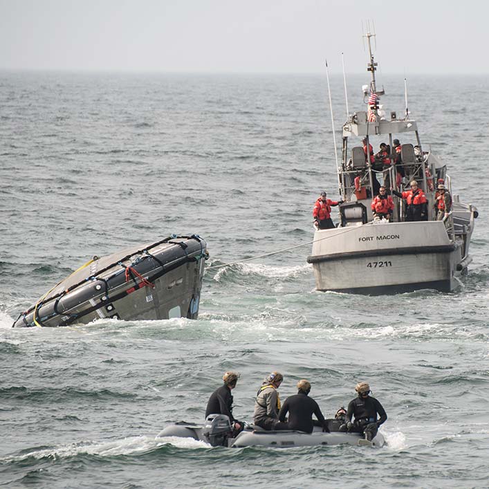 The spacecraft is upside down as boats head to rescue it.