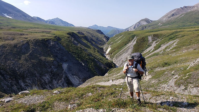 A man hiking with mountains in the background