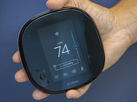 A hand holding an ecobee smart thermostat