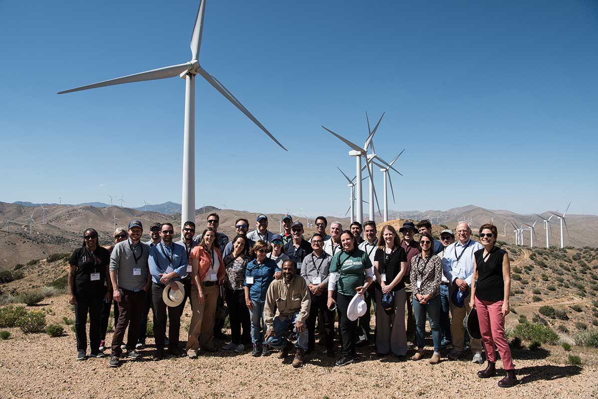 Photo of a group of people standing at a wind farm