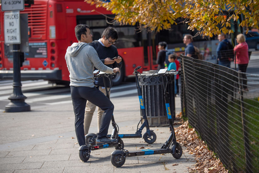 Two men using electric scooters