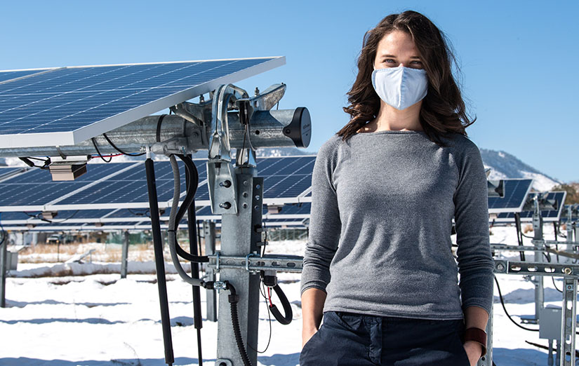A woman stands next to a PV array at NREL.