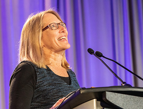 A woman speaks in front of a microphone.