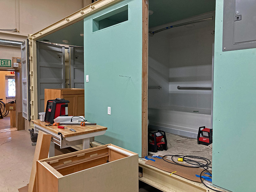 Photo of a bathroom and kitchen module being constructed inside a shipping container