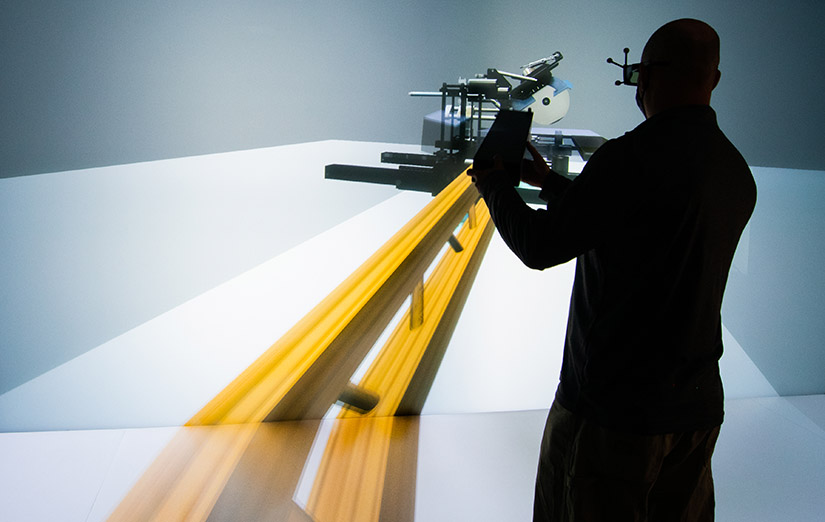 Photo of a researcher interacting with a digital virtualiaztion of an automated cut-saw machine