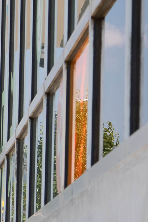 Photo of an outdoor wall of windows on a building, with one colored orange that contains quantum dot solar technology