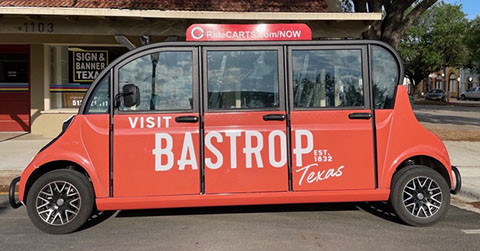 Photo of a red ecab painted with the words "Visit Bastrop, Texas"