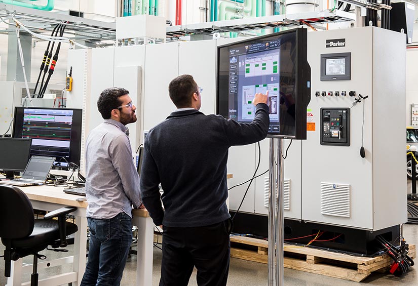 Photo of two researchers interacting with a simulated microgrid control monitor.