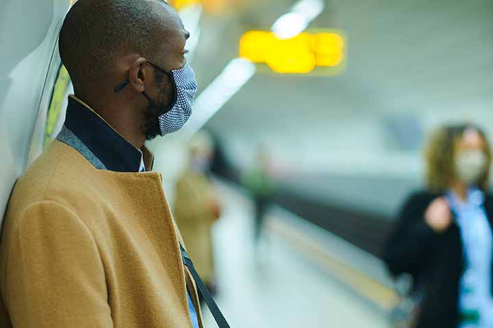 A male commuter on his way to work by underground wearing a face mask