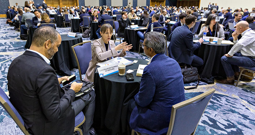 A large room full of people speaking together at separate small tables