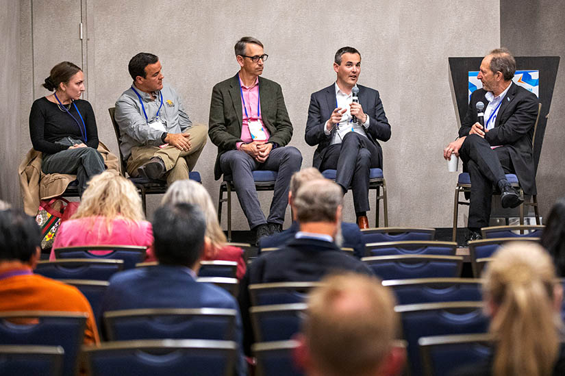 Five people seated on stage and speaking during a panel