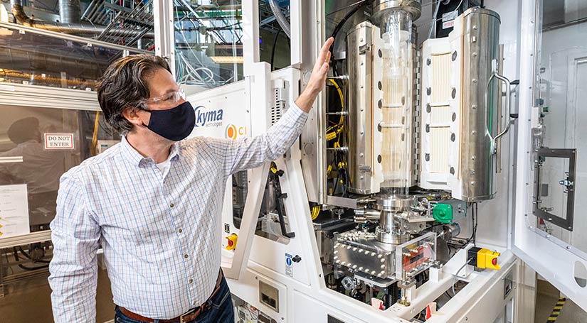 Photo of a researcher pointing to a piece of equipment in a laboratory.