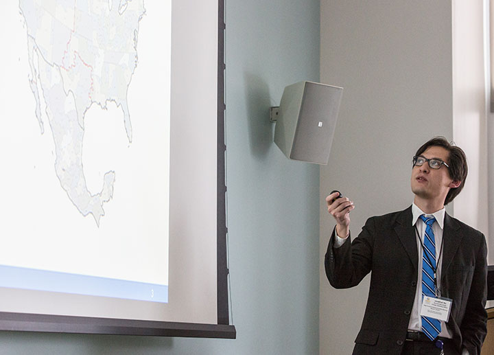 A researcher presenting and looking at a projector screen that shows the U.S. map.