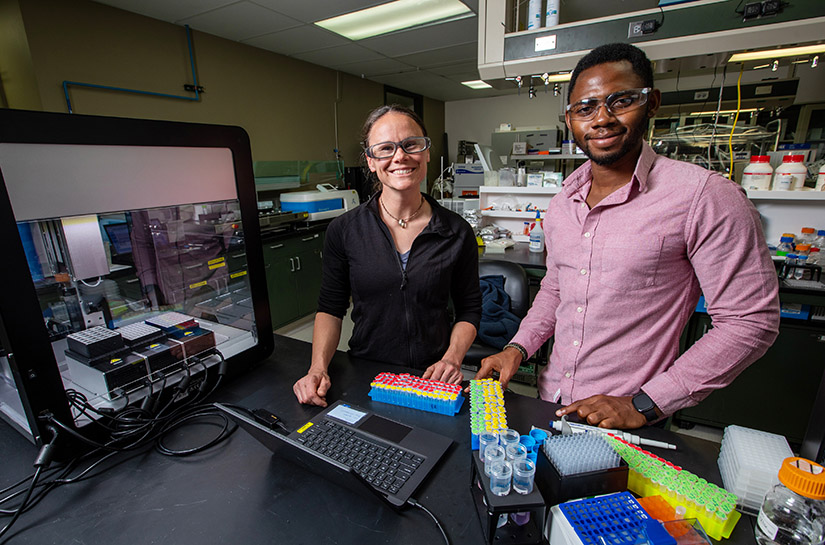 Two people stand inside a laboratory.