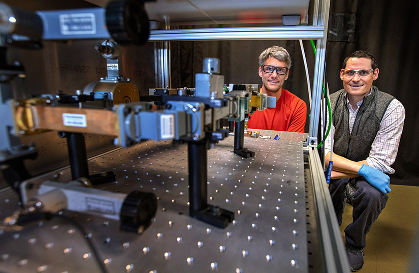 Two men examine a piece of laboratory equipment they created.