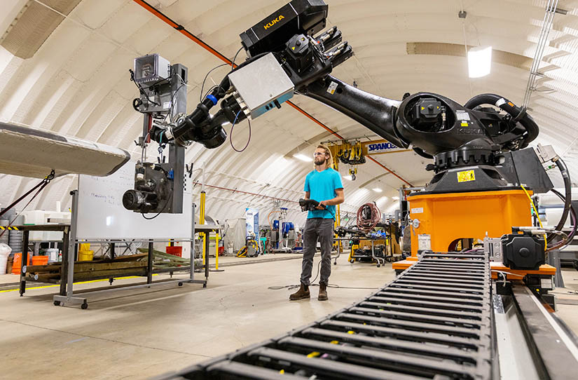 Photo of a man remote-controlling a robotic arm in a lab