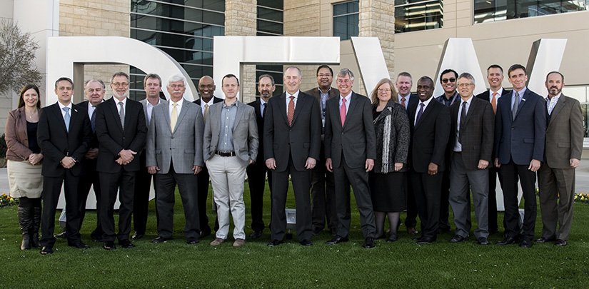 Photo of 20 people standing in front of a "DFW" sign