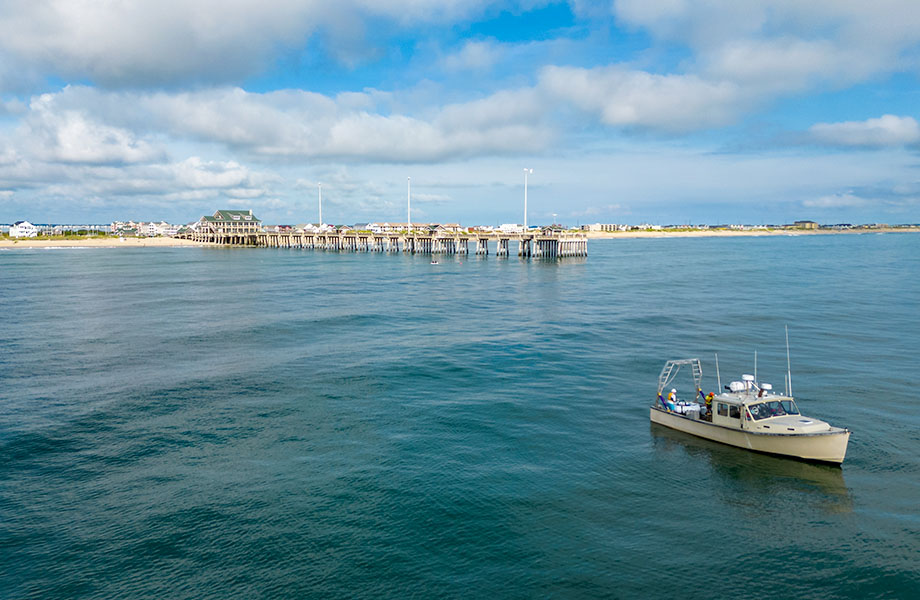 A boats floats in the water near a pier.