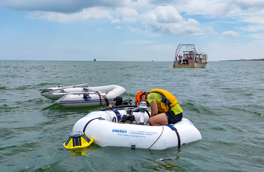 A man sits hunched over on the WEC device,  floating in the sea.