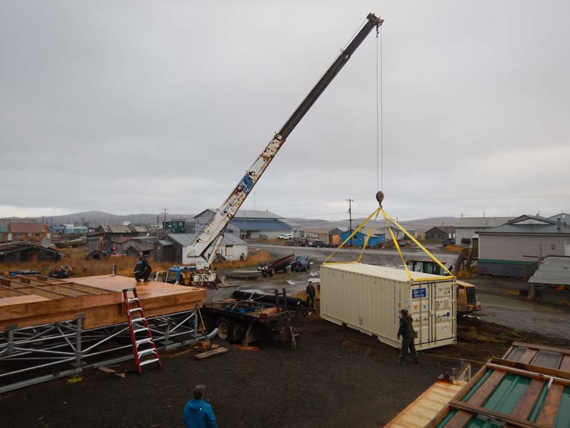 A crane lowering a shipping container into place.