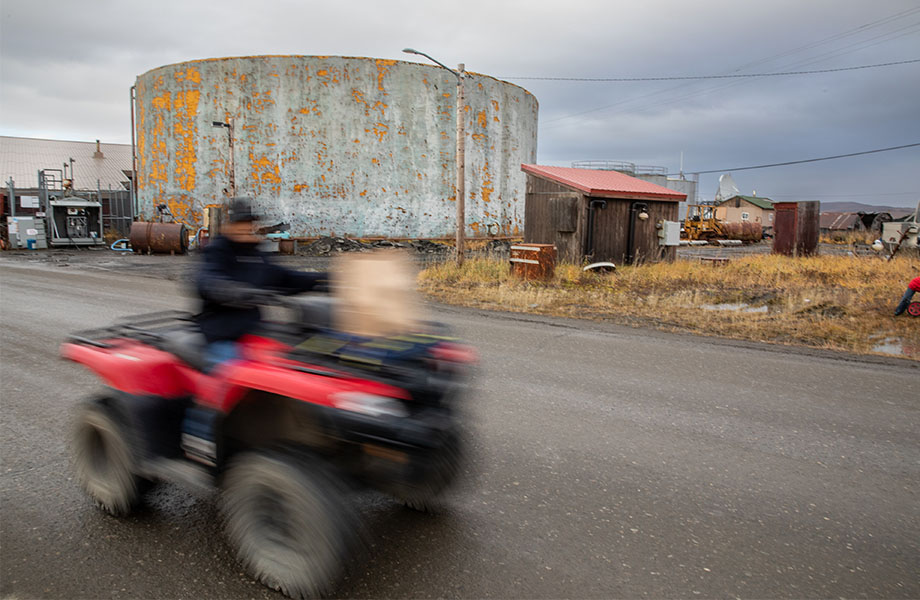 A blurred figure on an ATV zooms by old buildings