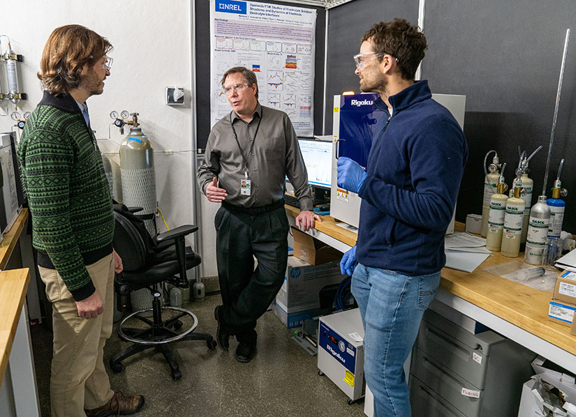 Three researchers stand and talk.