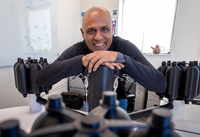 Send Sirnivas smiling with arms sitting atop the base he developed for a prototype of a floating wind turbine.