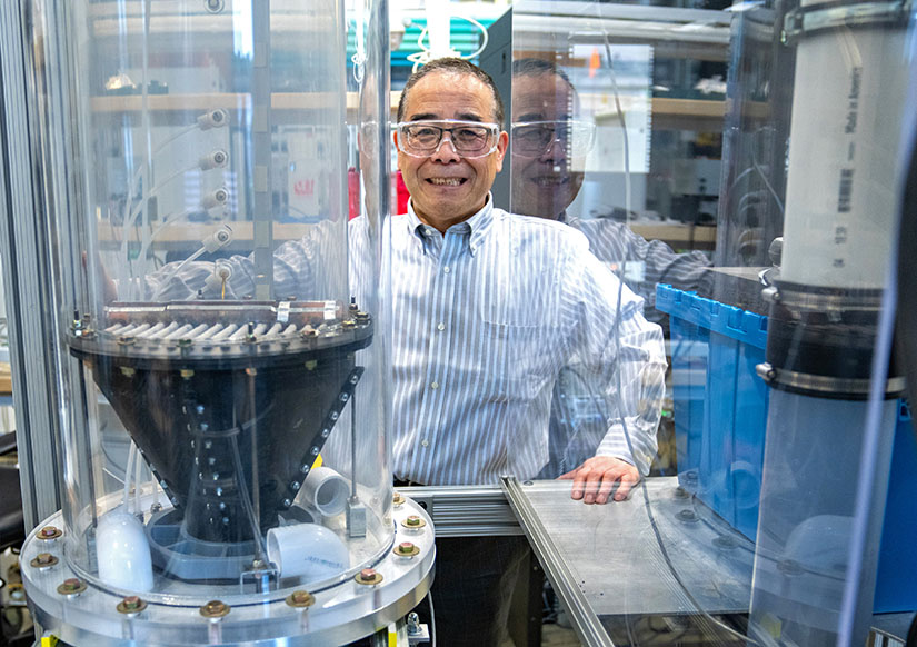 A man stands behind a large glass column.