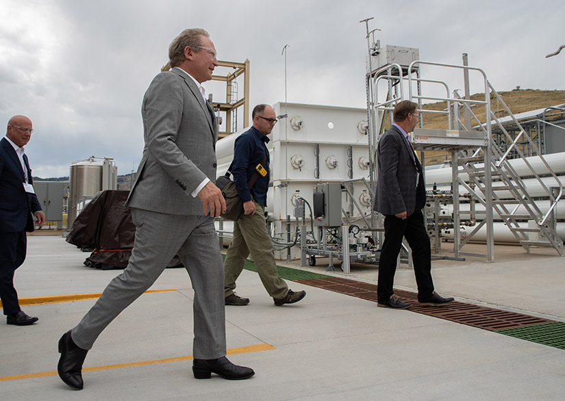 A group of people walking in front of a hydrogen fuel station.