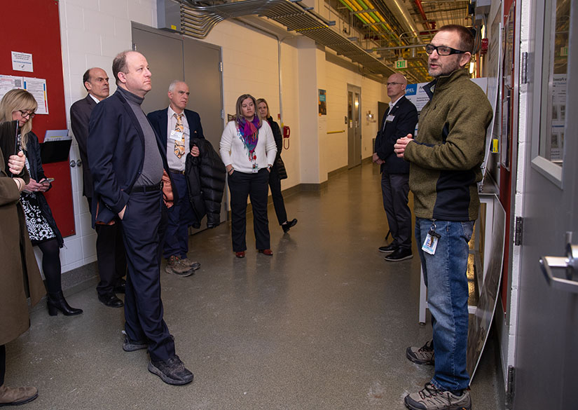 A group of people listen to a researcher while on a tour of NREL.