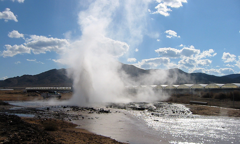 An image of a hot spring in front of greenhouses in the mountains.