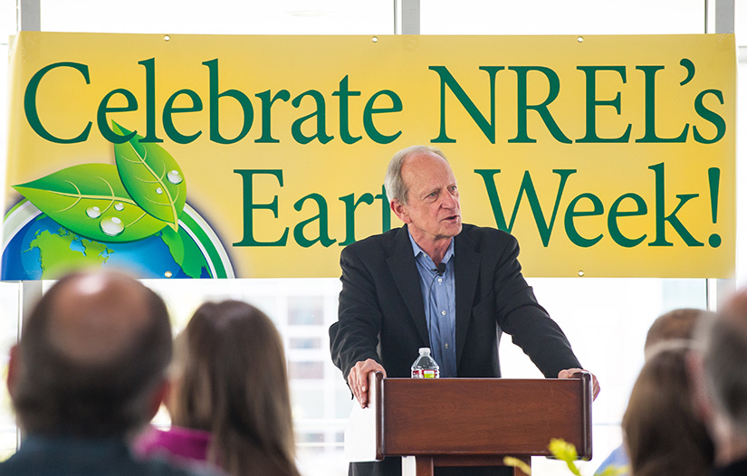 Denis Hayes speaks at a podium. A sign with the words Celebrate NREL's Earth Week! is behind him.