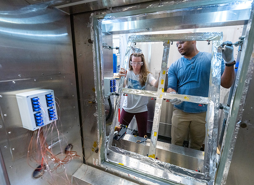 A woman and a man are shown installing an insulating glass unit into a test chamber.