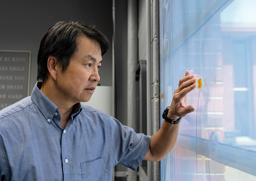 A man examines a sensor affixed to a window.