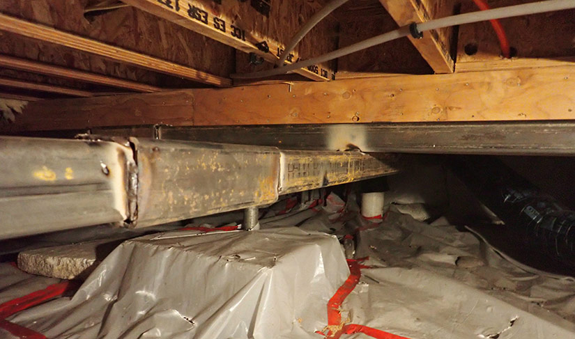 Photo of steel beams installed under a house to stiffen and level the foundation