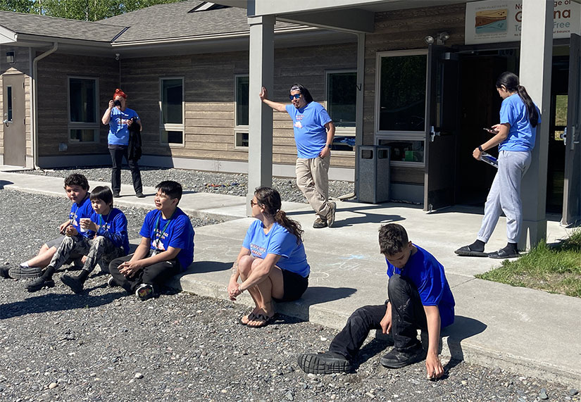 Photo of a group of people standing and sitting outside of a building