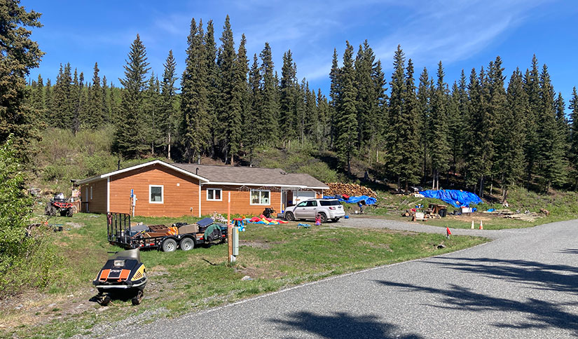 Photo of a house on an Alaskan hillside surrounded by forest trees