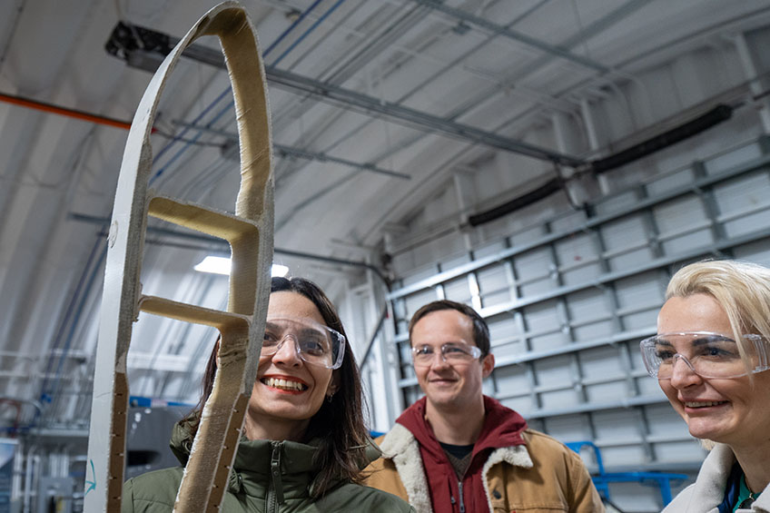 Three people smile while holding an object.