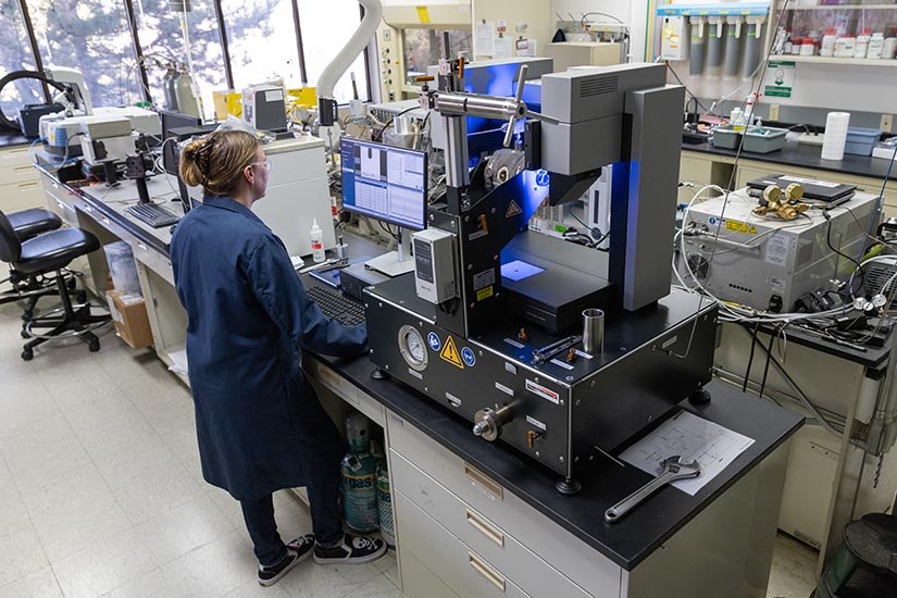 A woman standing at a lab bench operates research equipment