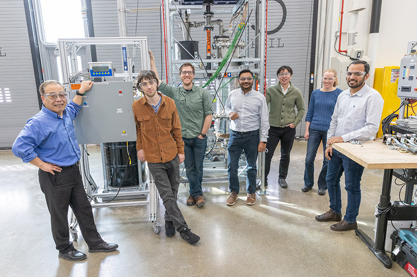 A group of seven people stand next to a piece of scientific equipment.