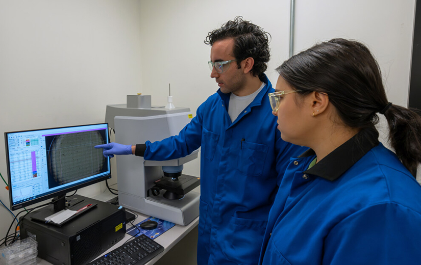 Two researchers look at a computer screen. 