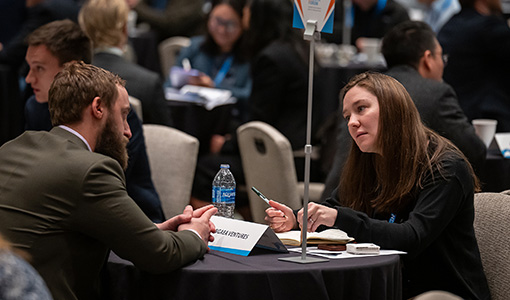 Two people sitting at a table speaking.