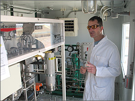 Photo of NREL researcher, Peter Gotseff, standing in front of Teledyne electrolyzer as he discusses the wind-to-hydrogen project which produces and stores hydrogen from electricity generated by wind power.