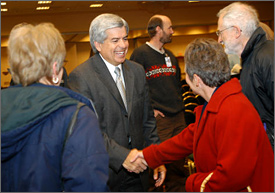 Photo of a man shaking hands as several people gather around him.