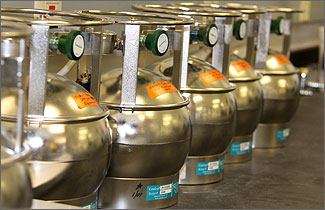 Photo of a round metal storage canisters with valves on top.