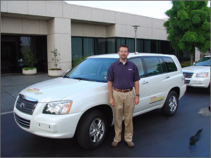 Photo of a man standing in front of a white SUV.